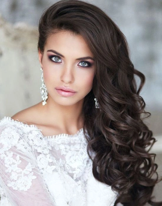 Side swept curls paired with an asymmetrical gown for holiday elegance