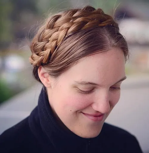 Milkmaid braids holiday hairstyle for a cozy Christmas cabin trip A woman with milkmaid braids smiles warmly by a Christmas tree in a cozy cabin