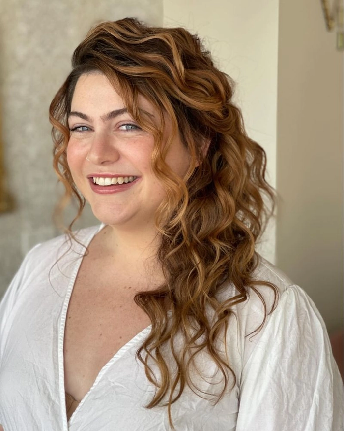 Side swept curls paired with an asymmetrical gown for holiday hairstyle inspiration