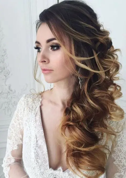 Side swept curls paired with an asymmetrical gown for holiday elegance
