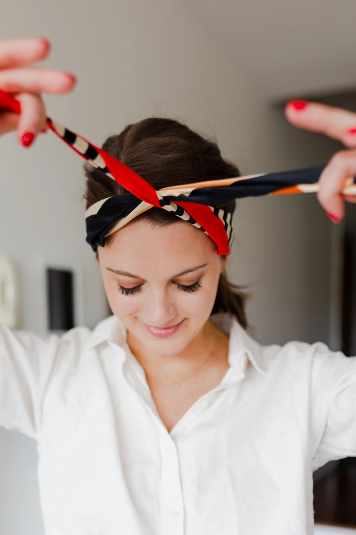 Woman with curly hair wrapped in a silk scarf for winter hair protection, holiday hairstyle step