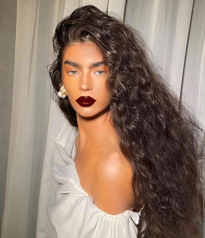 Sleek wet look hairstyle with sharp center part and glossy finish inspired by villain aesthetics for holiday glamour