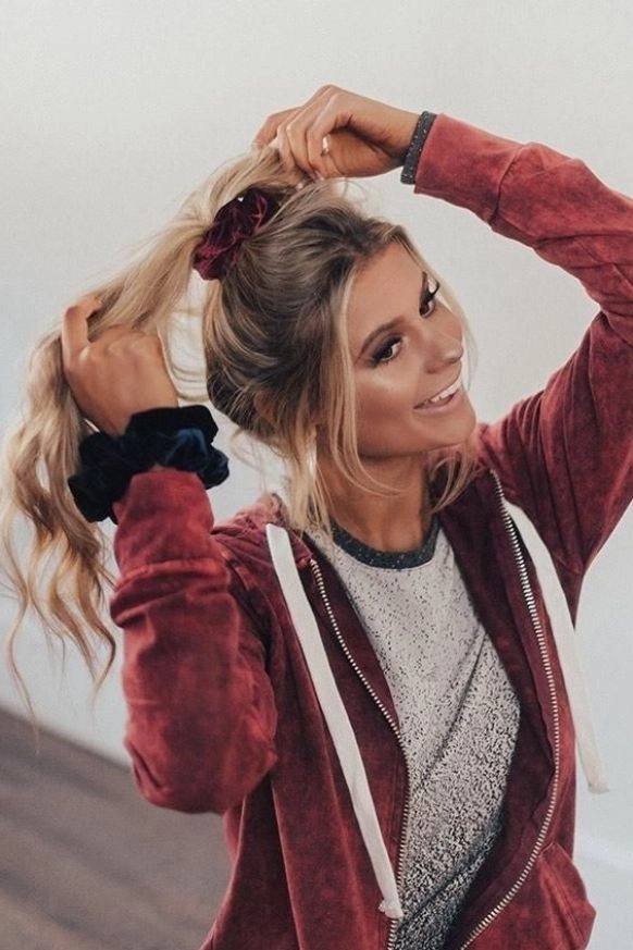 Velvet Scrunchie Styling for Casual Holiday Hair Outings Women with a velvet scrunchie in a loose, casual holiday hairstyle during a festive outdoor outing