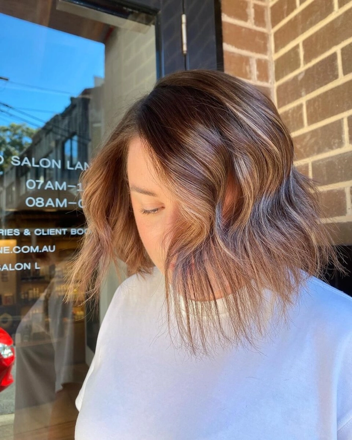 A woman with a textured lob hairstyle at an autumn birthday party, featuring warm highlights and soft waves