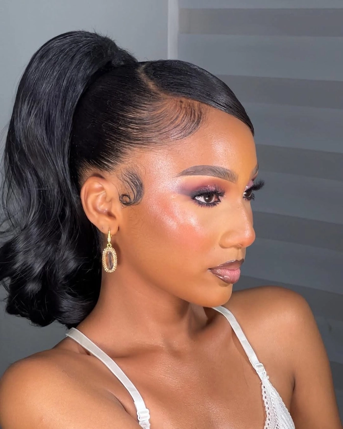 A woman with a sleek high ponytail in cocktail attire, styled for a party