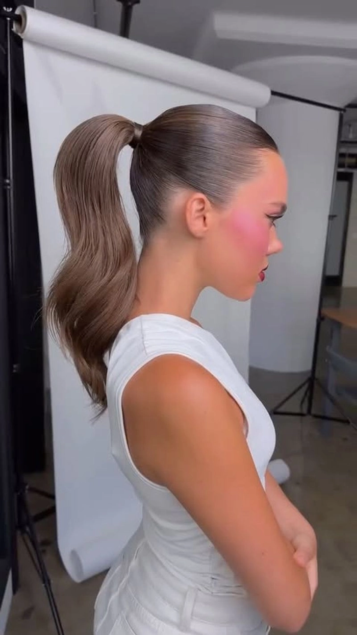 Woman with sleek high ponytail and elegant cocktail attire for a party