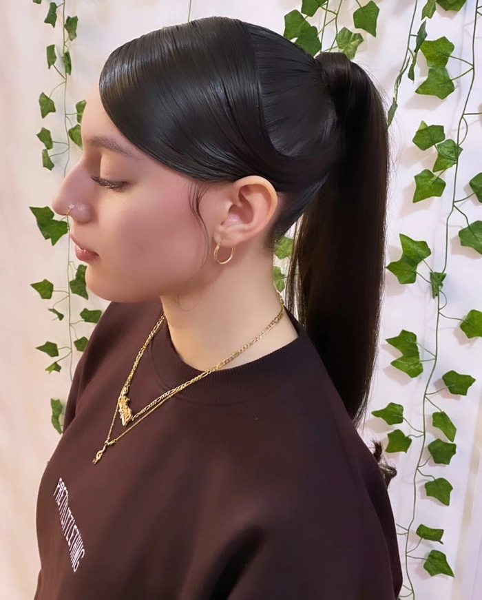 A woman wearing cocktail attire with a sleek high ponytail hairstyle for a party.