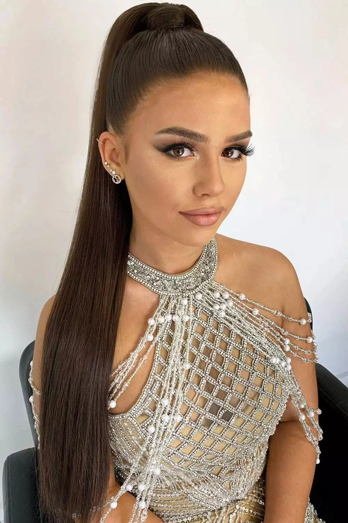 Model wearing cocktail attire with a sleek high ponytail hairstyle