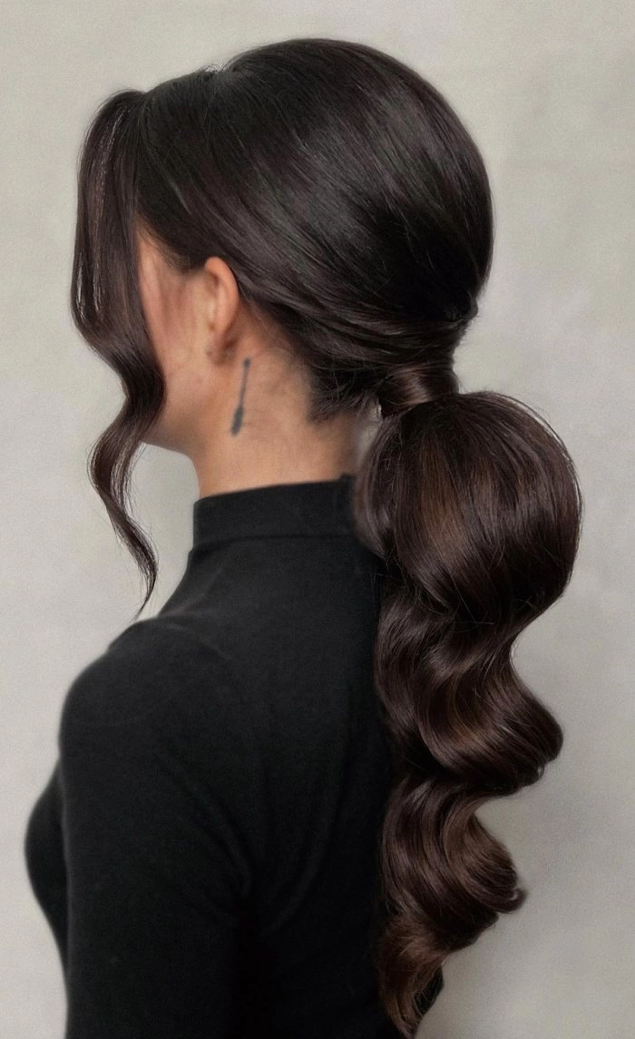 A sleek high ponytail paired with elegant cocktail attire creates a polished party hairstyle.