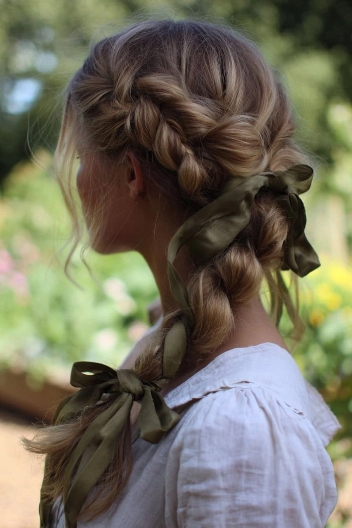 A young woman with cascading cottagecore festival braids intertwined with colorful ribbons