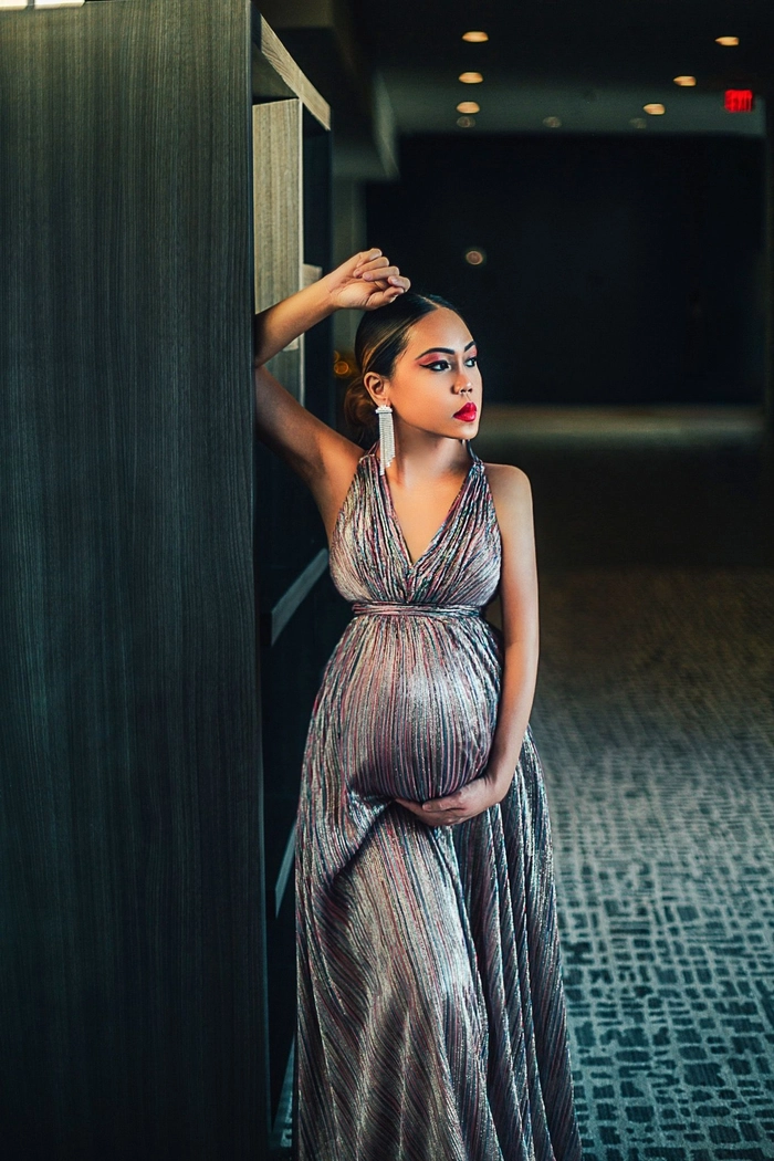 Glamorous maternity party hairstyle with sparkling accessories A pregnant woman with a chic side-swept curly updo and glittering hairpins at a party