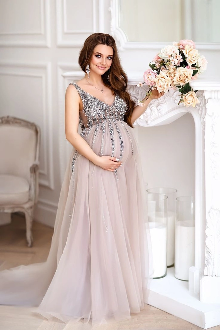 Glamorous party hairstyle for expectant mothers - stylish updo A pregnant woman with a glamorous updo hairstyle at a party, wearing a sparkling maternity dress
