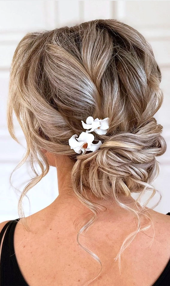 Low messy bun with face-framing pieces for a wedding guest hairstyle