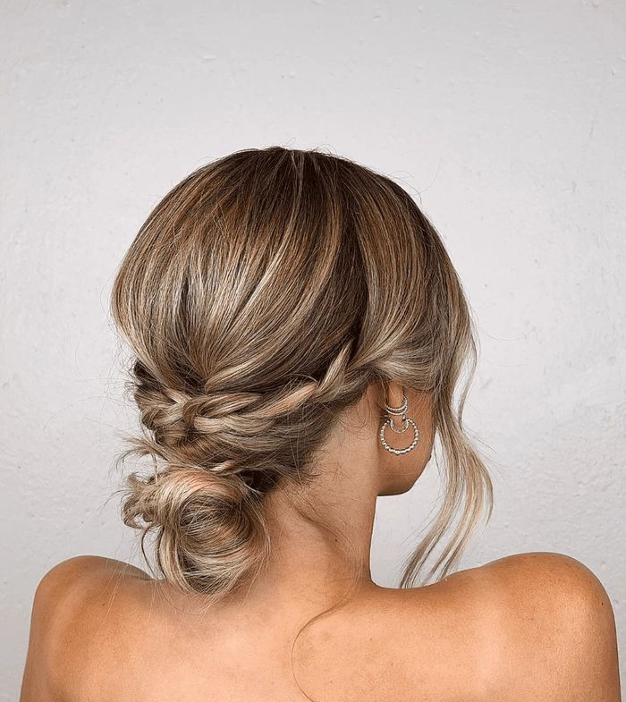 Low messy bun with face framing pieces for a wedding guest party hairstyle