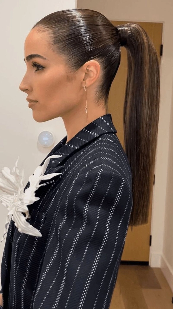 Woman with a sleek high ponytail wearing cocktail attire at a festive party