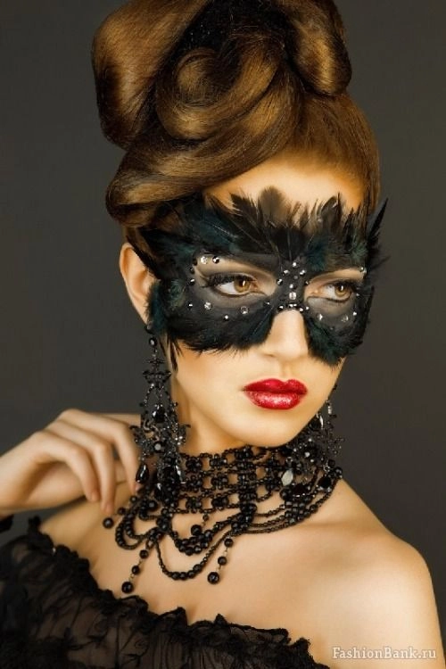 Masquerade party hairstyle featuring feather mask complementing elegant updo Elegant updo hairstyle with feather mask accessory for masquerade ball