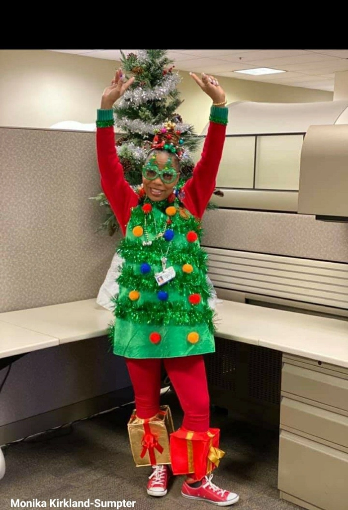 A woman with a festive updo and sparkly hair accessories posing in an ugly Christmas sweater at a holiday party
