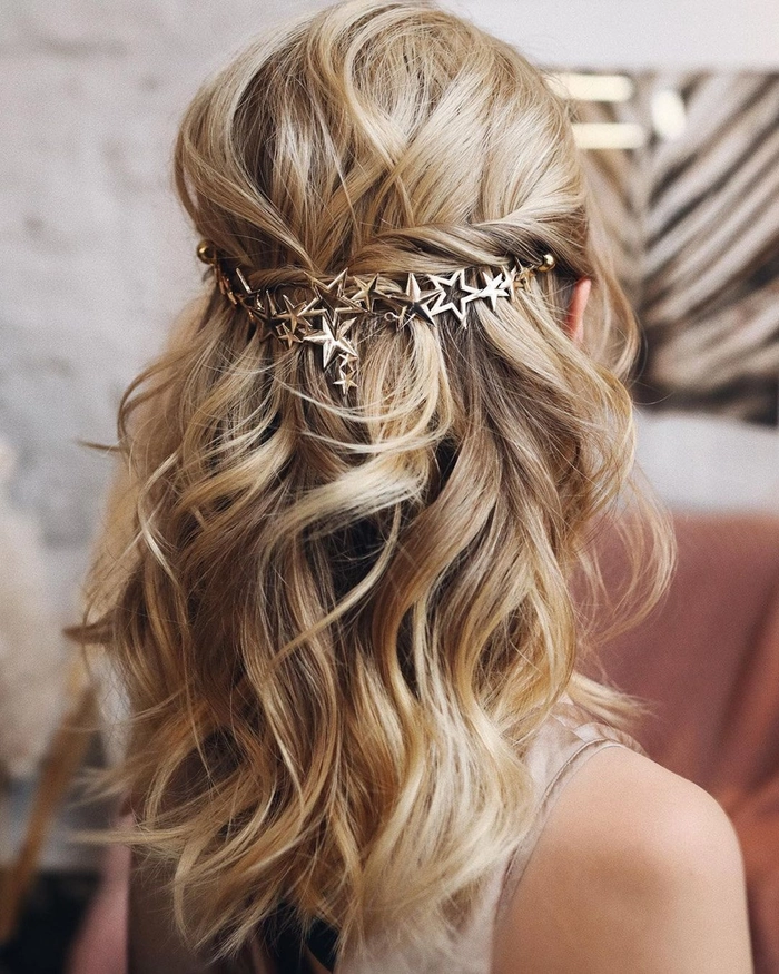 Elegant wedding guest hairstyle for frizzy hair with soft waves and side accessory