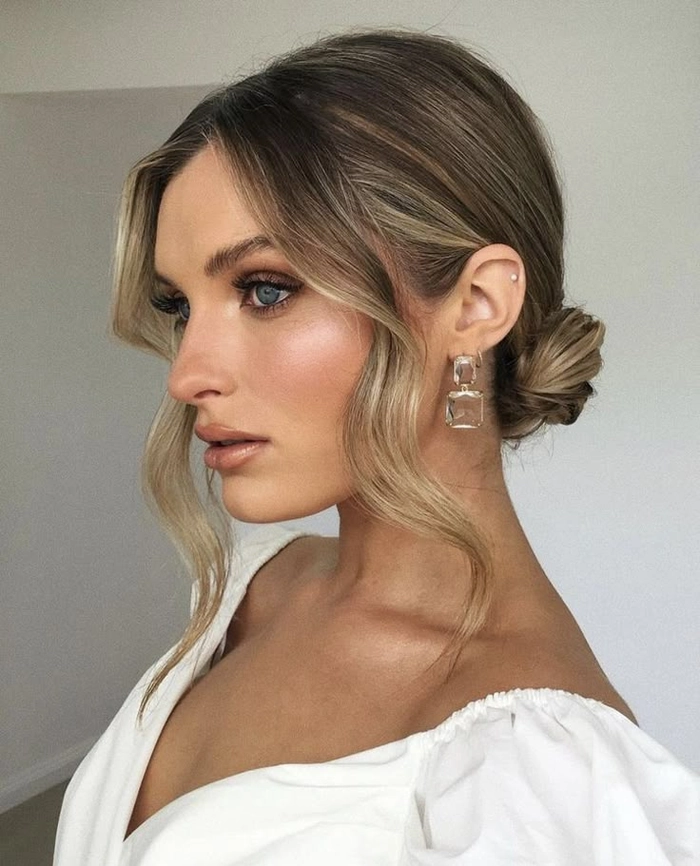 Elegant low messy bun with soft face-framing pieces for a wedding guest hairstyle
