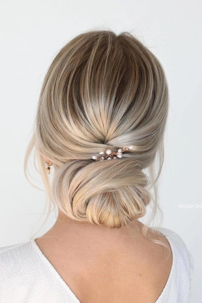Refined wedding guest updo on pastel pink hair with soft braids and floral details Pastel pink hair styled in an elegant updo with twisted sections and pearl accents for a wedding guest