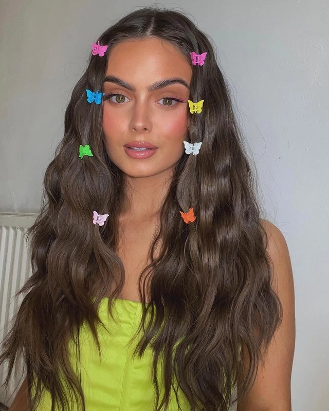 y2k party hairstyle with colorful butterfly clips and a slicked-back ponytail for a clubbing look