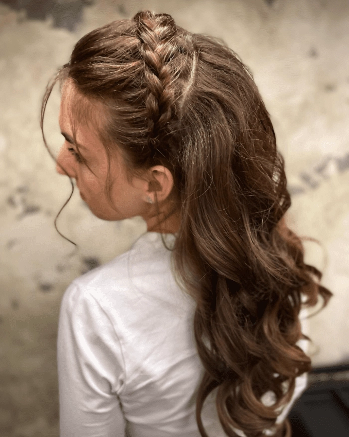 Chic and timeless prom look with a detailed Dutch braid design Elegant prom hairstyle featuring a Dutch braid woven into loose curls