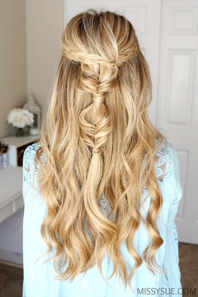Elegant prom hairstyle featuring a fishtail braid woven through cascading curls