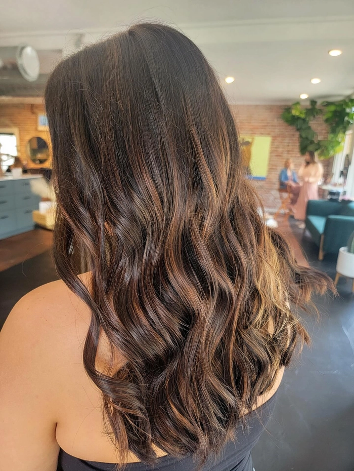Elegant prom hairstyle showcasing dark brunette balayage with soft curls