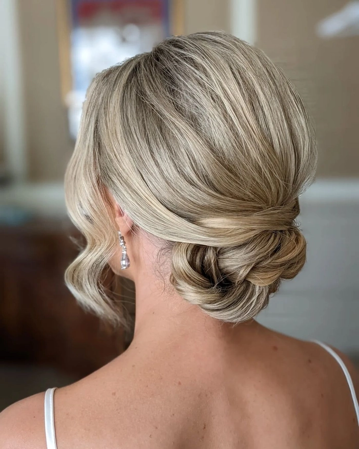 Elegant prom hairstyle featuring a low nape bun adorned with soft curls
