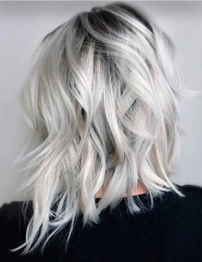 Elegant prom hairstyle for platinum blonde hair with soft curls and a delicate hair accessory