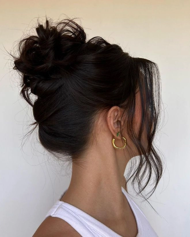 Elegant prom hairstyles with a high messy bun showcasing textured waves and volume
