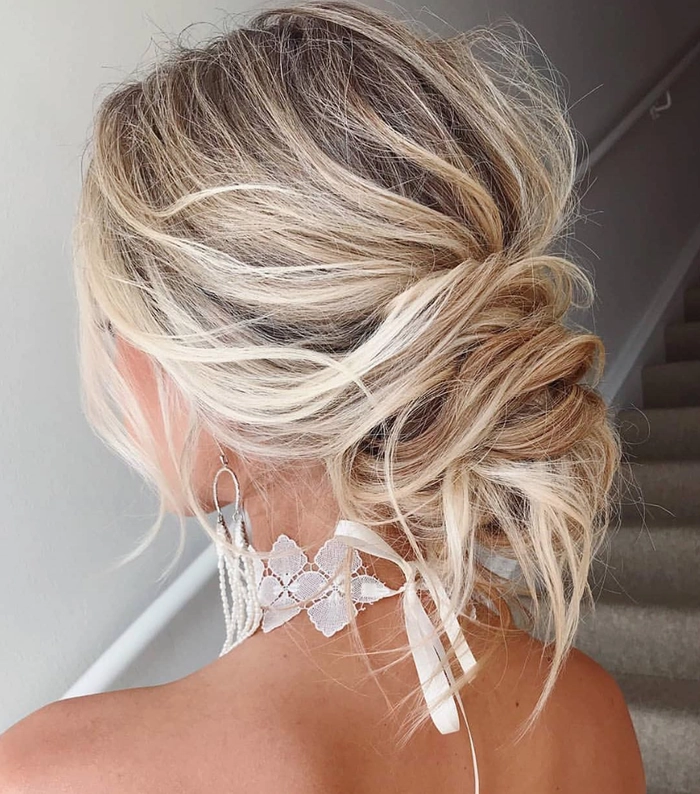 Elegant prom hairstyle featuring a high messy bun with loose curls