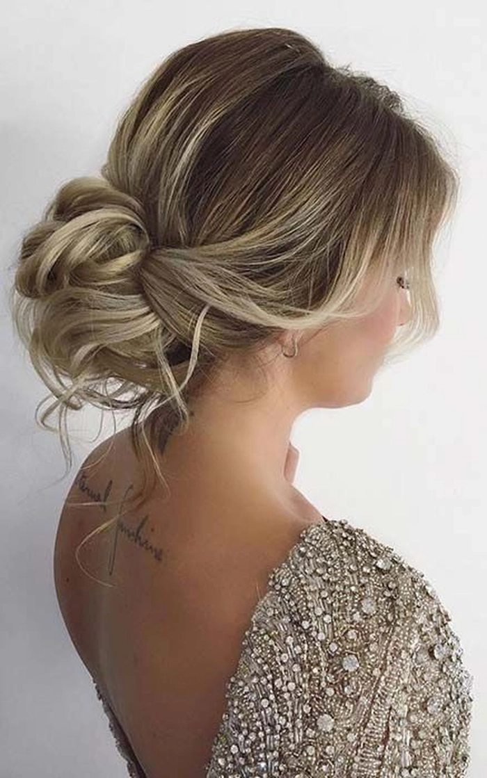 Elegant prom hairstyle featuring a high messy bun with loose strands for a chic look