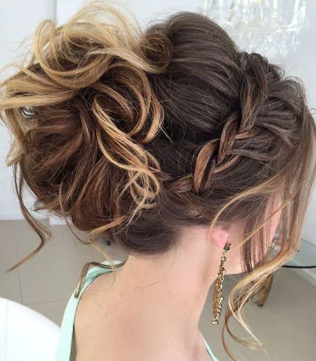 Elegant prom hairstyle featuring a high messy bun with loose curls
