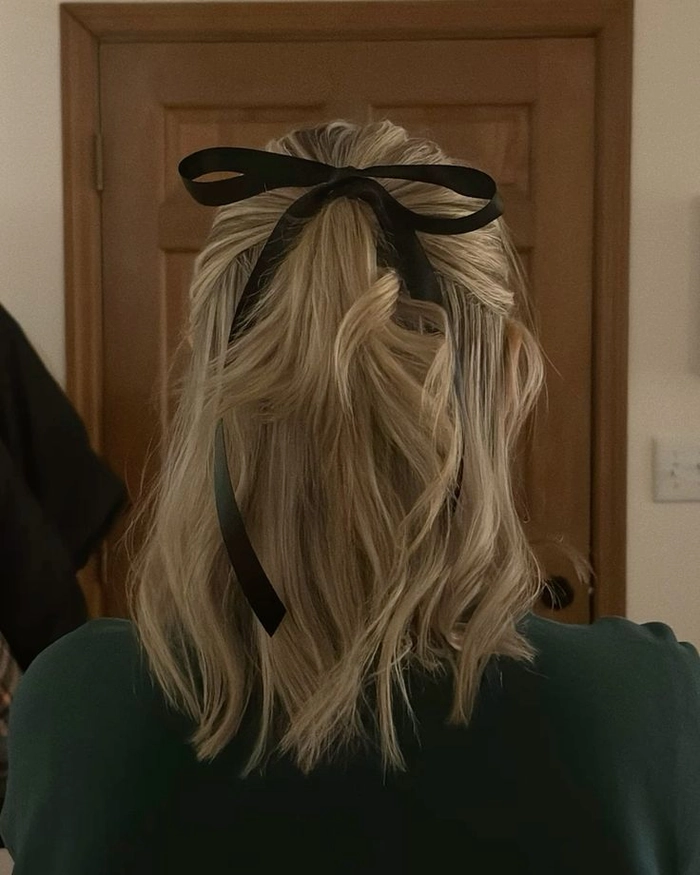 Elegant prom hairstyle featuring soft curls and a velvet ribbon accessory