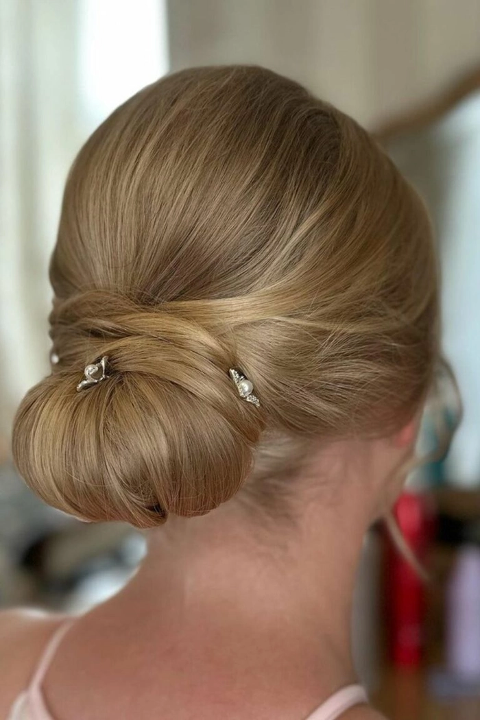 Sophisticated low chignon hairstyle perfect for prom and formal events Elegant low chignon prom updo with soft curls and delicate hair accessories