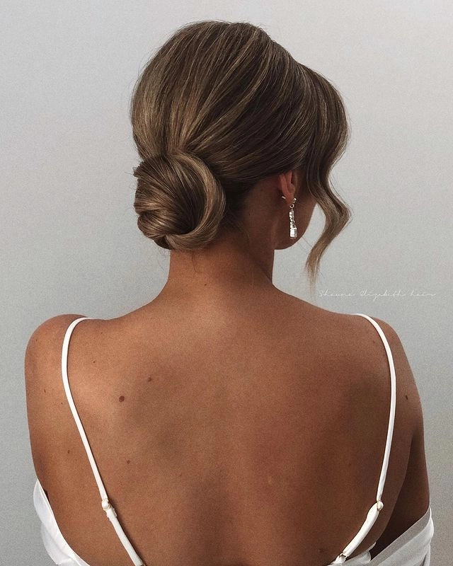 Textured top knot prom hairstyle perfect for a chic and stylish look Elegant textured top knot prom updo with delicate wisps and volume