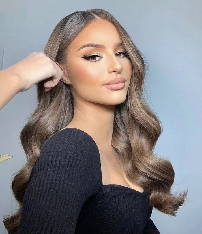 Elegant voluminous blowout prom hairstyle featuring soft waves and plenty of volume