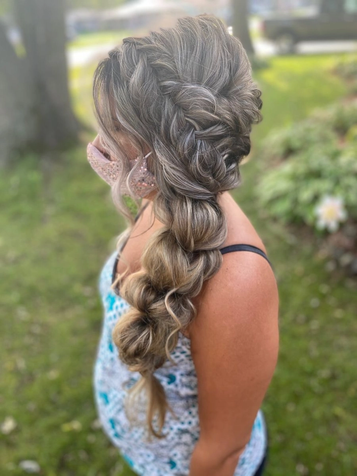Elegant fishtail braid prom hairstyle with soft waves and floral accents