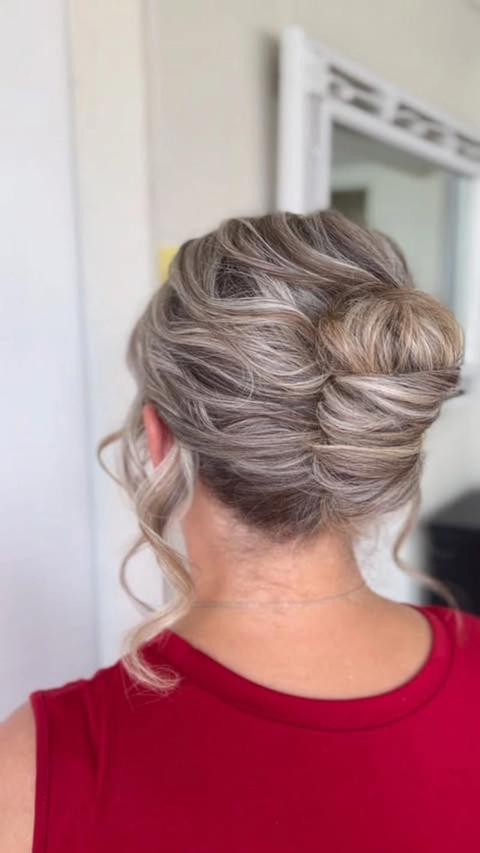 Messy French twist prom hairstyle with loose curls and wispy strands