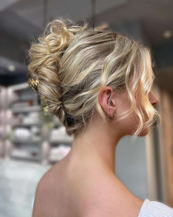 Messy French twist prom hairstyle with loose curls and delicate tendrils