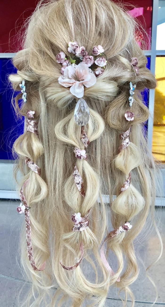 Romantic fairy tale princess prom hairstyle featuring soft curls and floral accessories