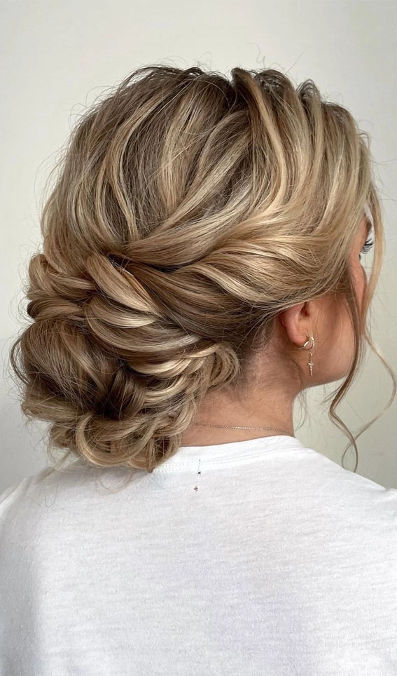 Prom hairstyle featuring a stylish textured top knot perfect for formal events Elegant textured top knot prom updo with intricate braiding and volume