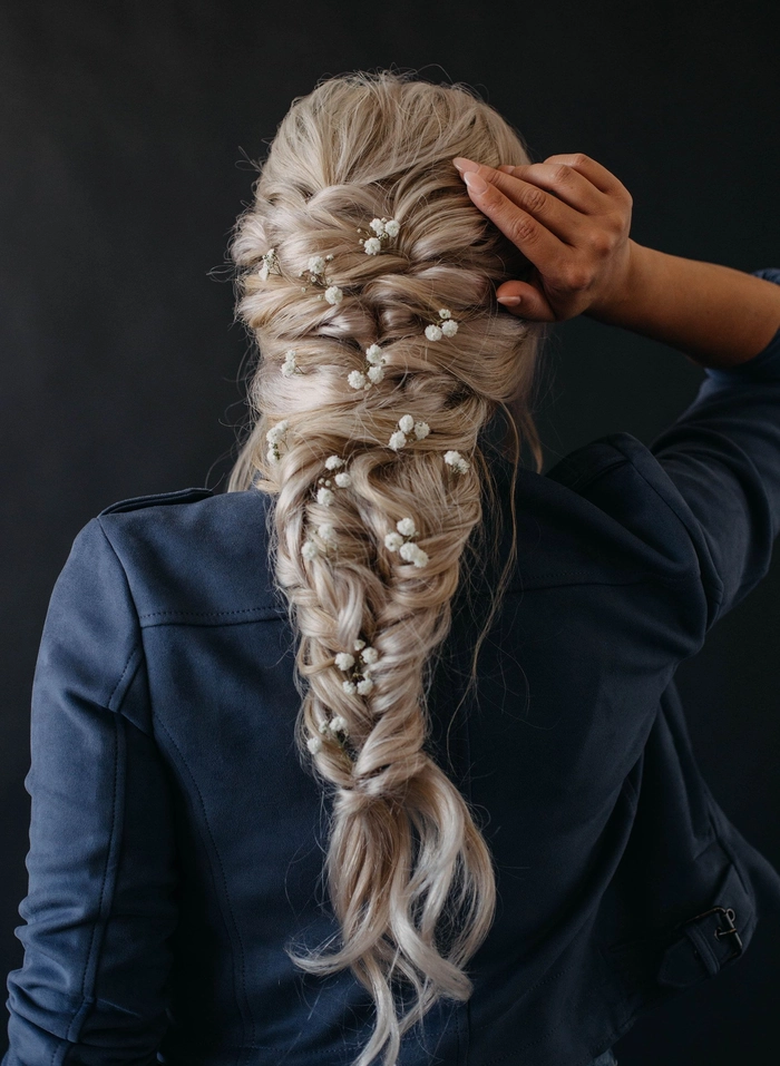 Boho braided wedding hair styled with loose waves and floral accents