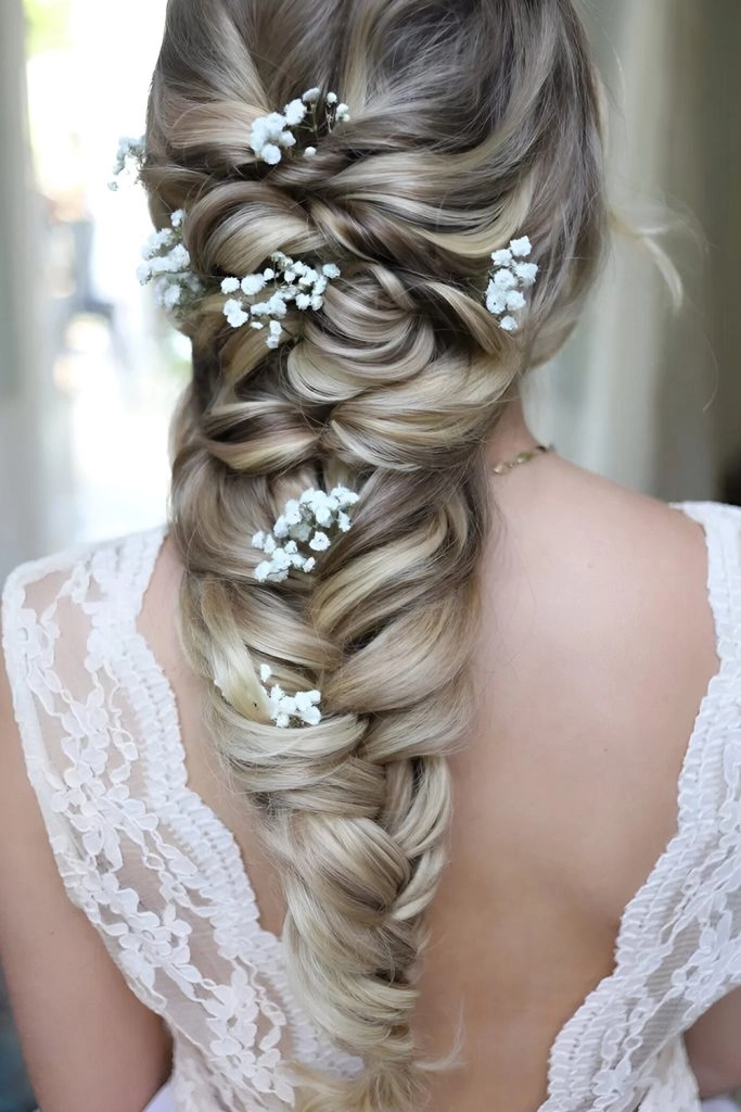 Boho braided wedding hair styled with loose waves and floral accents