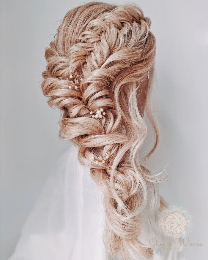 Boho braided wedding hair styled with loose waves and floral accents