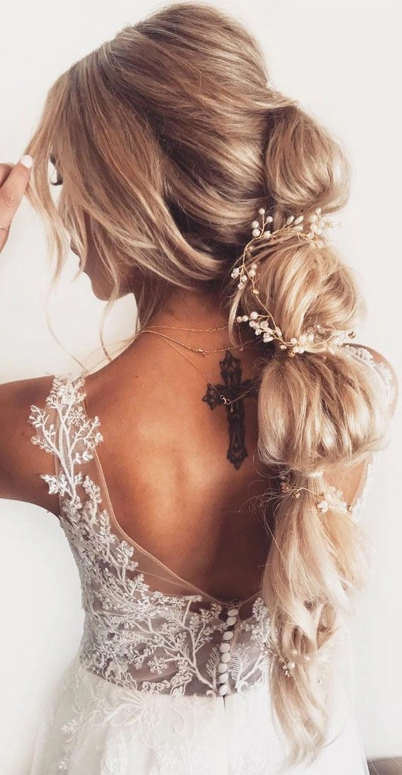 Bridal hair bubble ponytail styled with soft curls and delicate accessories