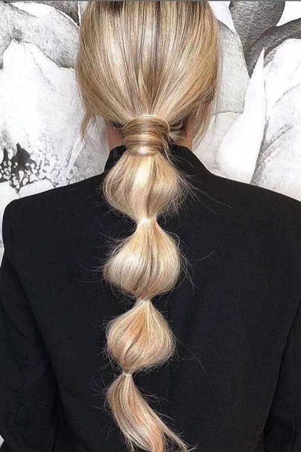 Elegant bridal hair bubble ponytail styled with soft curls and delicate accessories