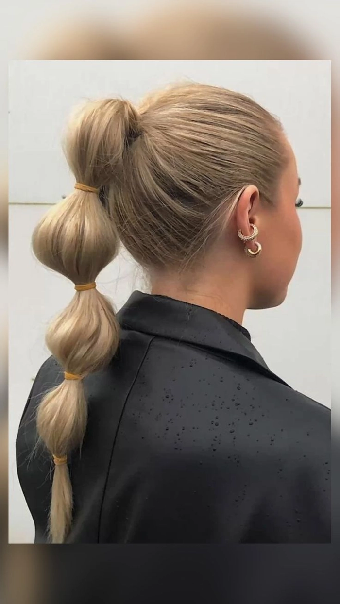Bride wearing an elegant bridal hair bubble ponytail with delicate floral accessories