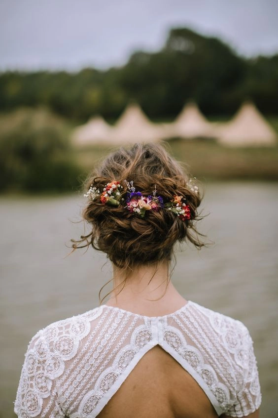 Bridal hairstyle with loose curls and floral accents for an outdoor rustic wedding